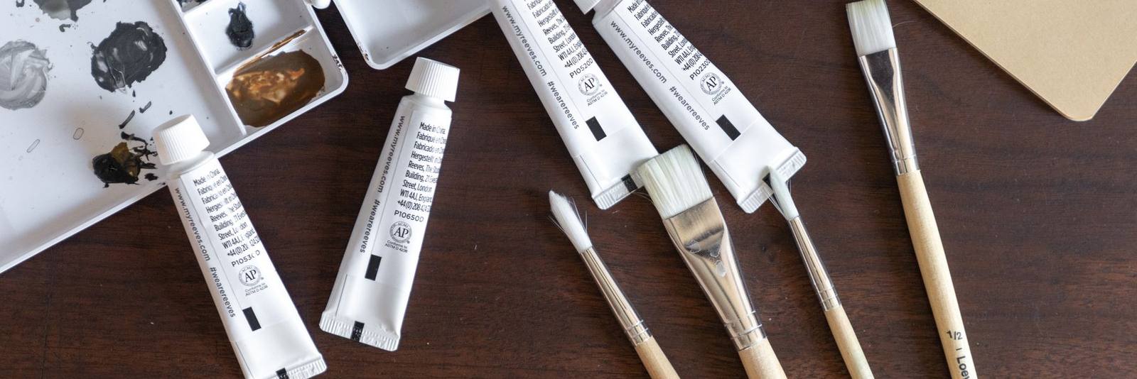 Paintbrushes and tubes of paint on a dark wooden table